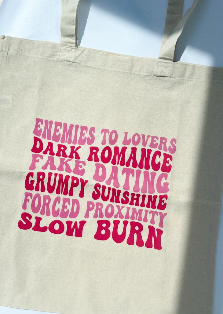 A captivating tote bag featuring a delightful collection of romance tropes awaits! Immerse yourself in the world of enemies-to-lovers, fake dating, grumpy sunshine, forced proximity, and slow burn themes with this enchanting tote. Perfect for avid book lovers, it allows you to stylishly carry your cherished romance novels while proudly showcasing your passion for the genre. Experience the magic of romance tropes and bookish surprises wherever you go with this irresistible tote!